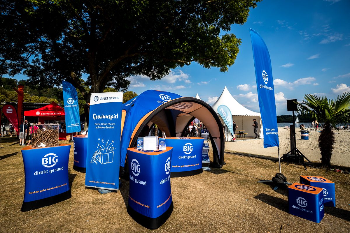 Der Stand des Gesundheitspartners am Ufer, dahinter die Wanderstrecke