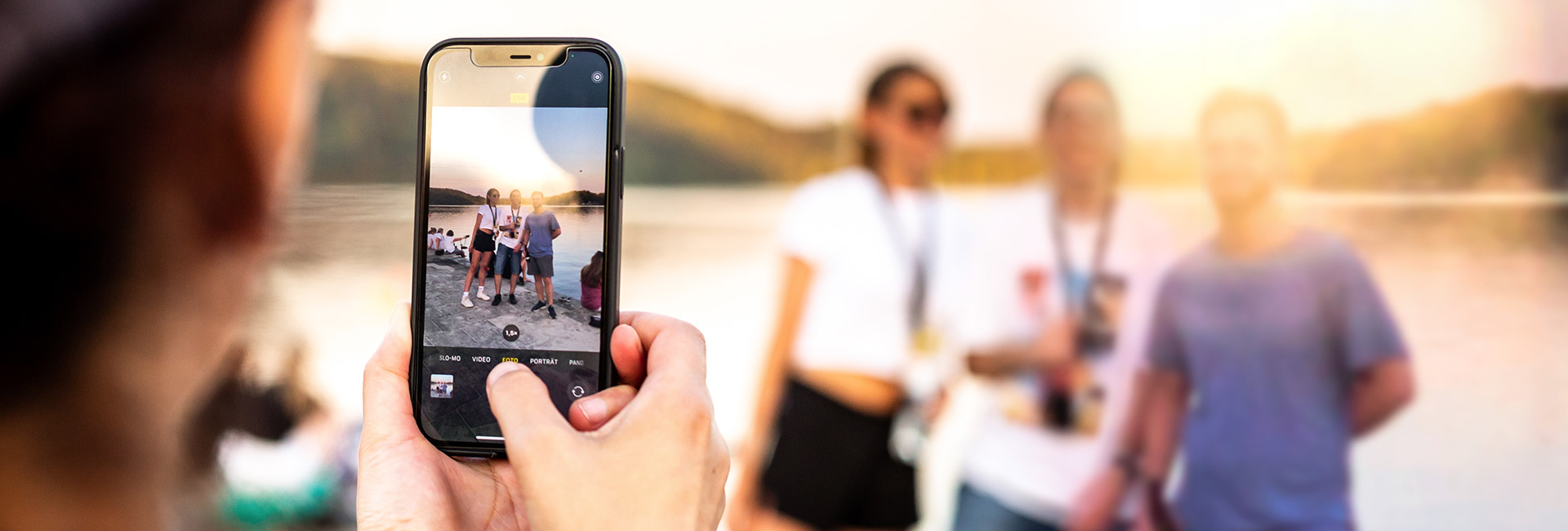 Zwei Teilnehmerinnen fotografieren sich mit dem Handy vor dem Abendlicht